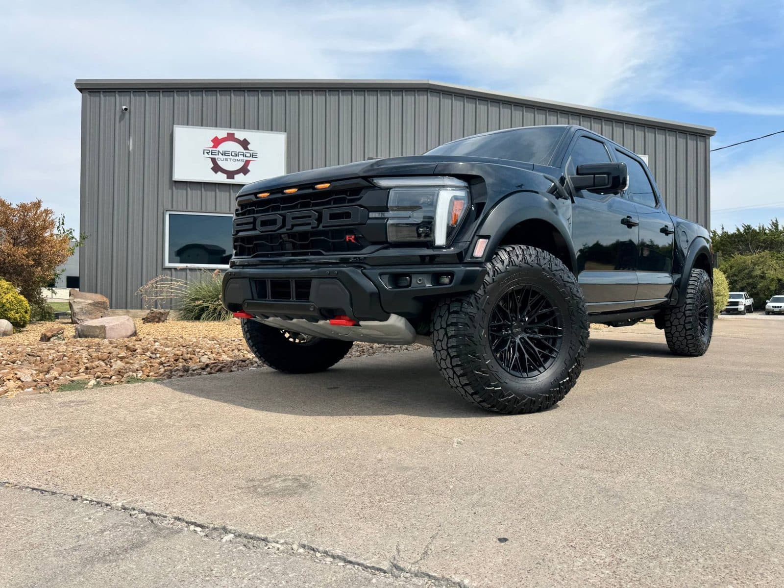 Black Ford F-150 Raptor R on gloss black Vossen wheels and 37-inch Falken Wildpeak R/T tires in front of the Renegade Customs shop, Rockwall TX