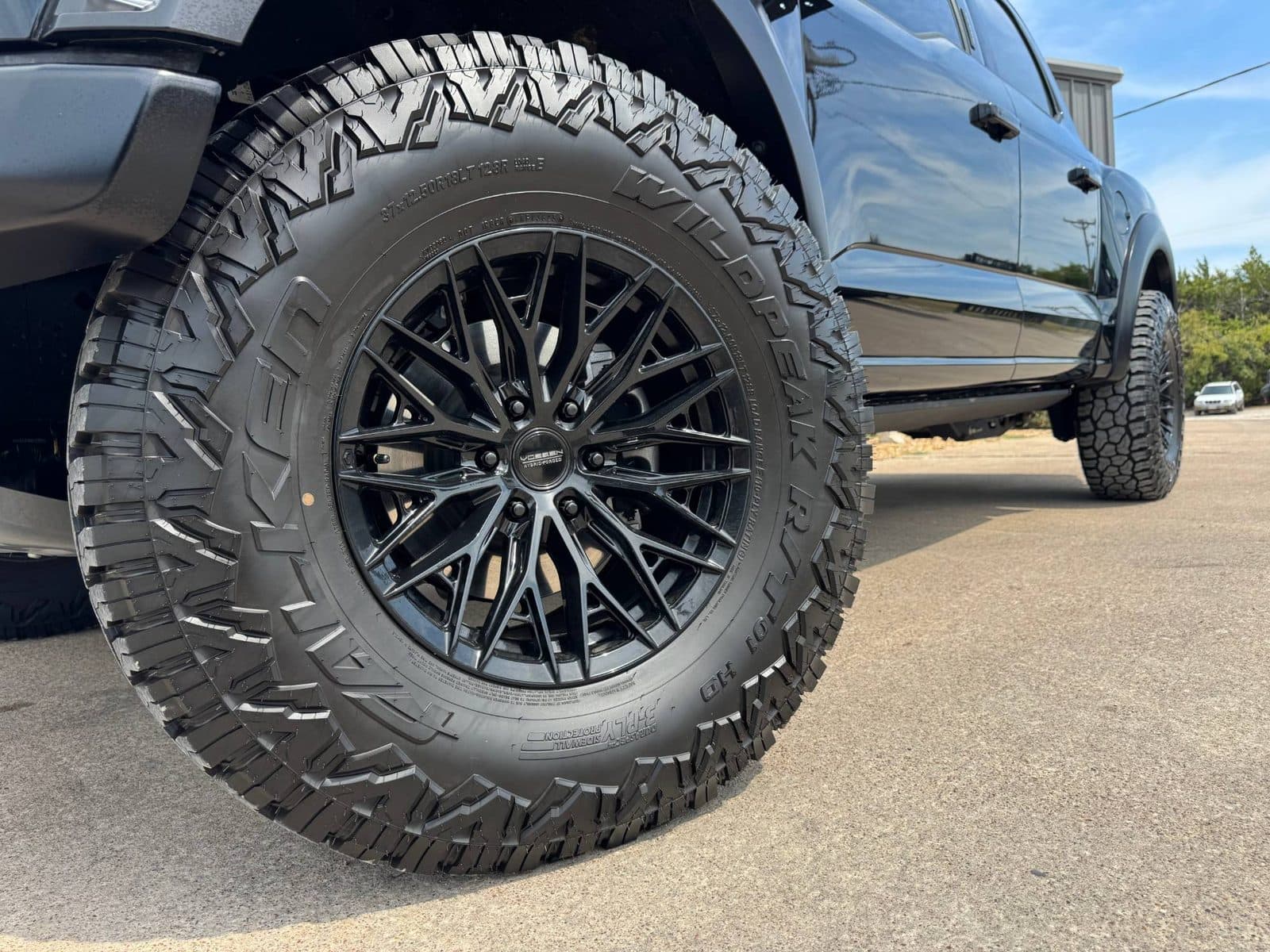 Close-up of a gloss black Vossen Hybrid Forged wheel on a 37x12.50R18 Falken Wildpeak R/T tire on a Ford Raptor R at Renegade Customs